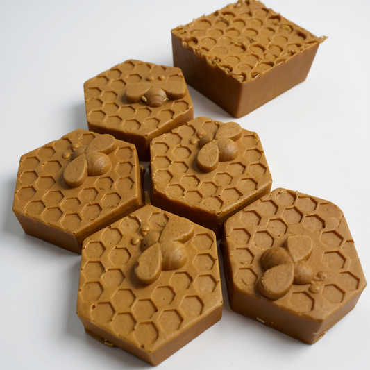 Hexagonal honeycomb-shaped candles with bee designs on a white background