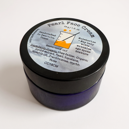 Jar of pearl face cream with a black lid on a white background