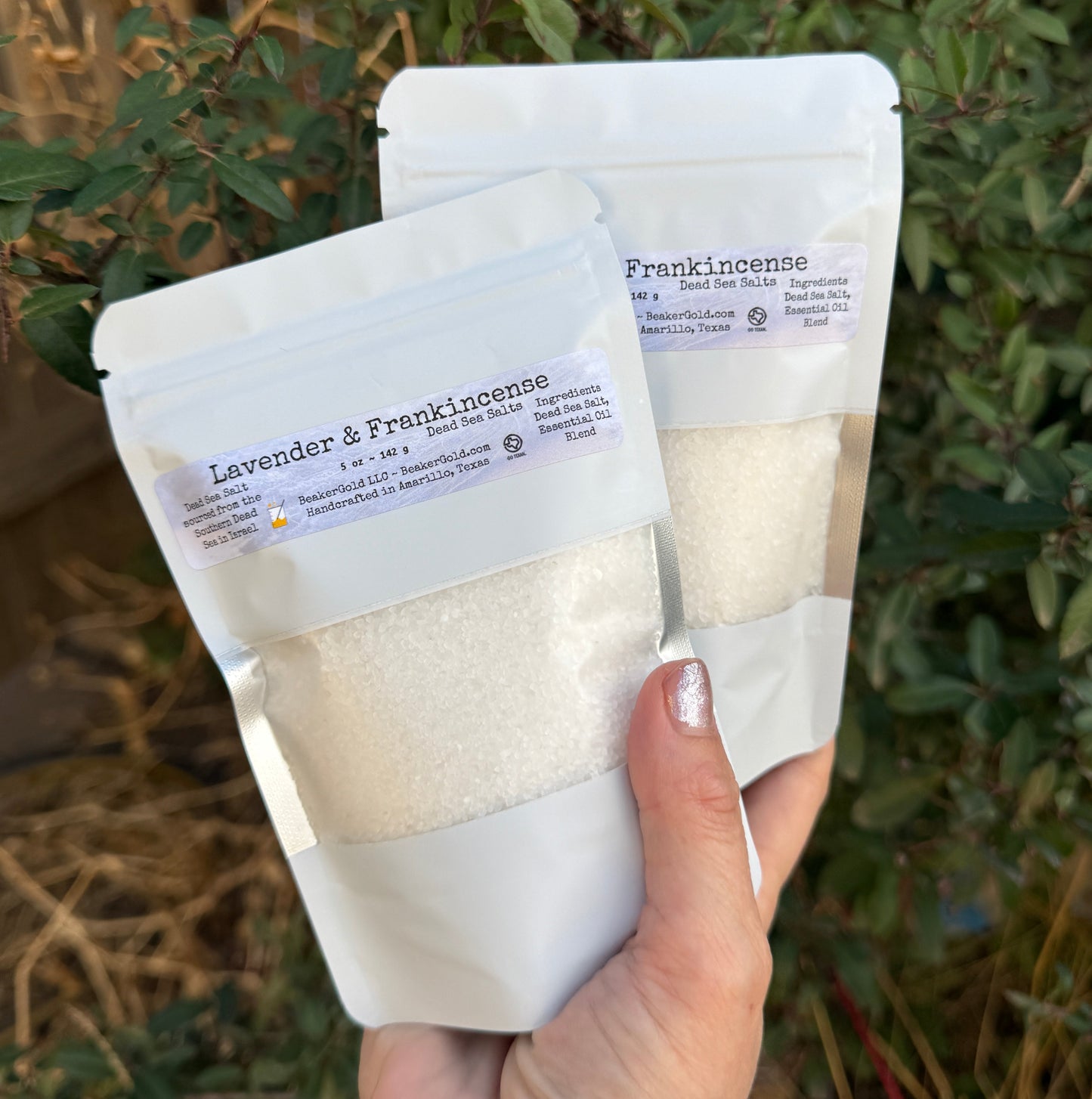 Hand holding a package of lavender and eucalyptus bath salts with a natural background