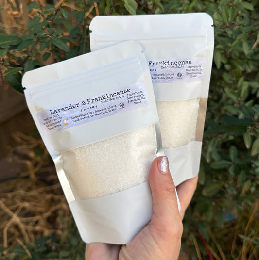 Hand holding a package of lavender and eucalyptus bath salts with a natural background