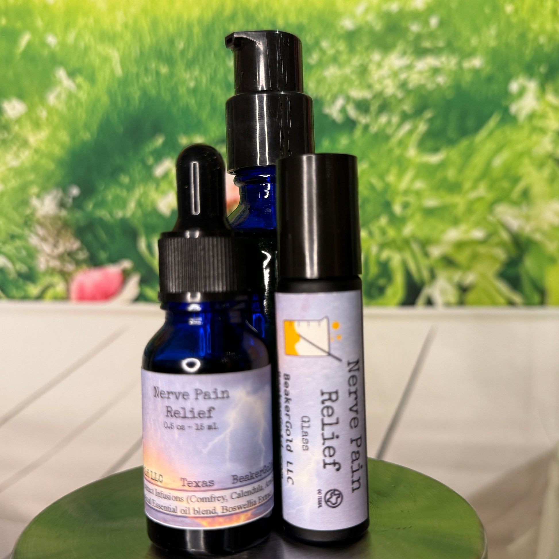 Two small bottles with droppers on a metallic surface with a green floral background.