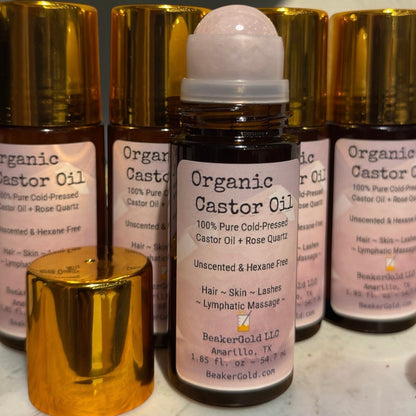 BeakerGold organic cold-pressed castor oil in Amber glass and rose quartz roller bottle for skin and lymphatic massage.